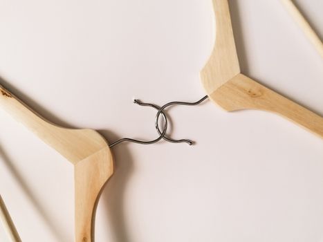 Elegant display of wooden hangers with hooks intertwined on light surface.