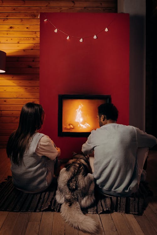 Couple Sitting Near Fireplace With Their Dog
