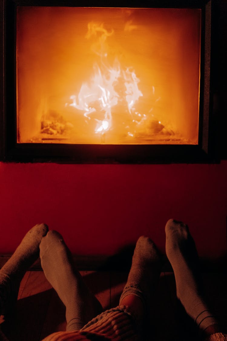 Couples Warming Feet Next To Fireplace