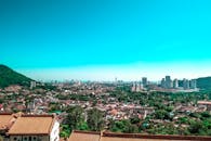 从上方俯瞰，明亮的城市景观和多样化的建筑在清澈的蓝天下尽收眼底