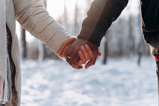 Close-up of a couple holding hands outdoors in a snowy winter setting, conveying love and togetherness.