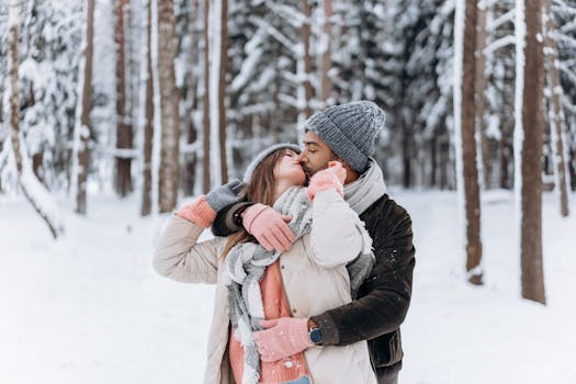 A couple sharing a loving embrace and kiss in a snowy winter forest setting.