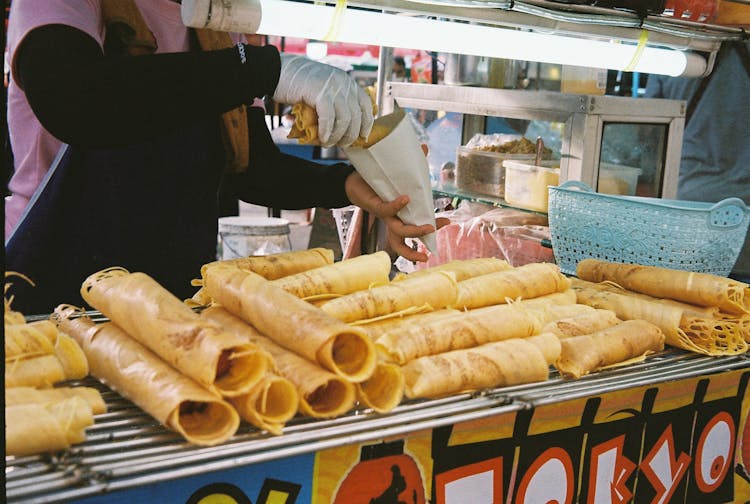 Woman Packing Food Into A Paper Bag On A Street Food Stall 