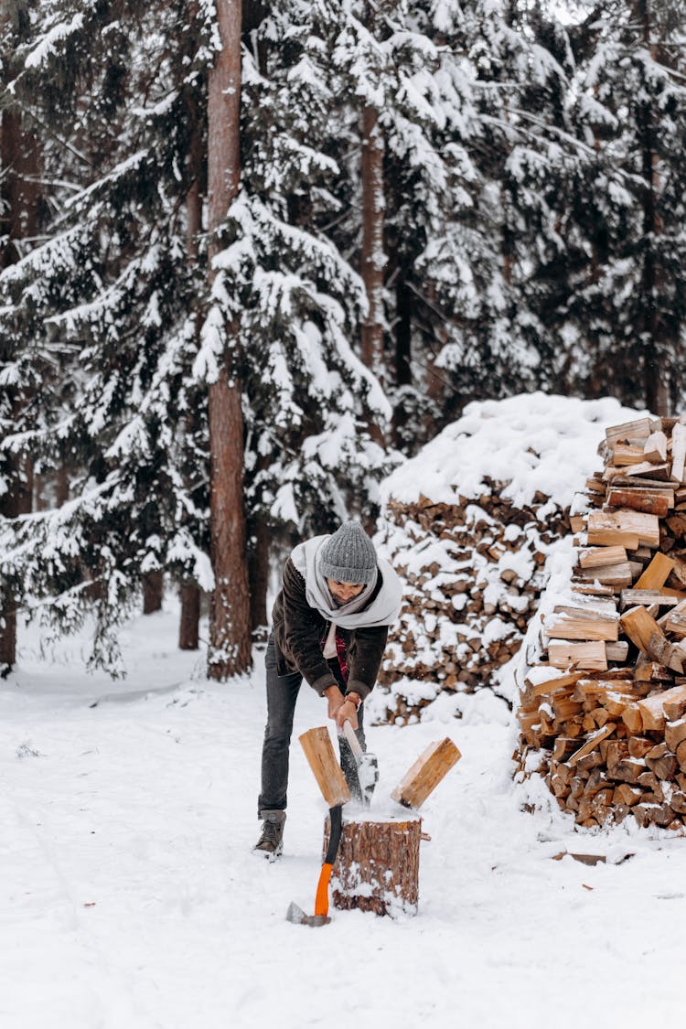 A Man Splitting Firewood With An Axe