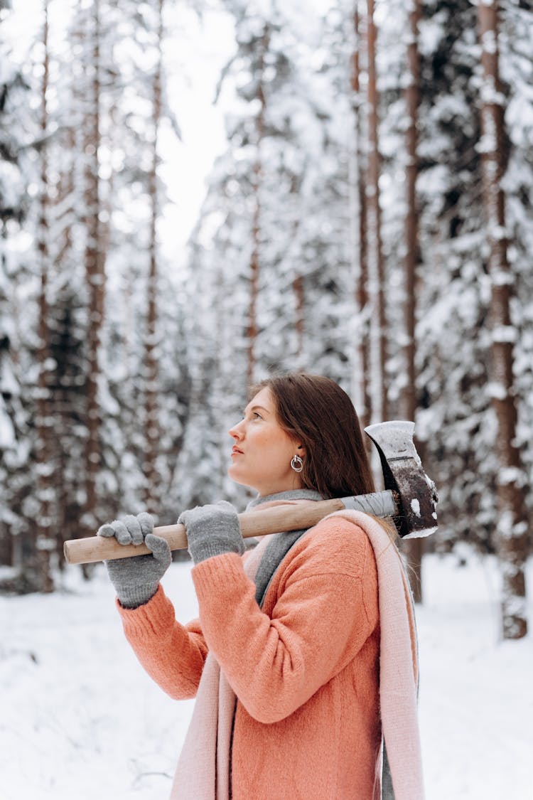 A Woman Holding An Axe In A Winter Forest