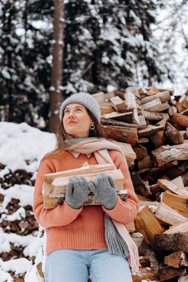 A Woman Holding Firewood In A Winter Forest