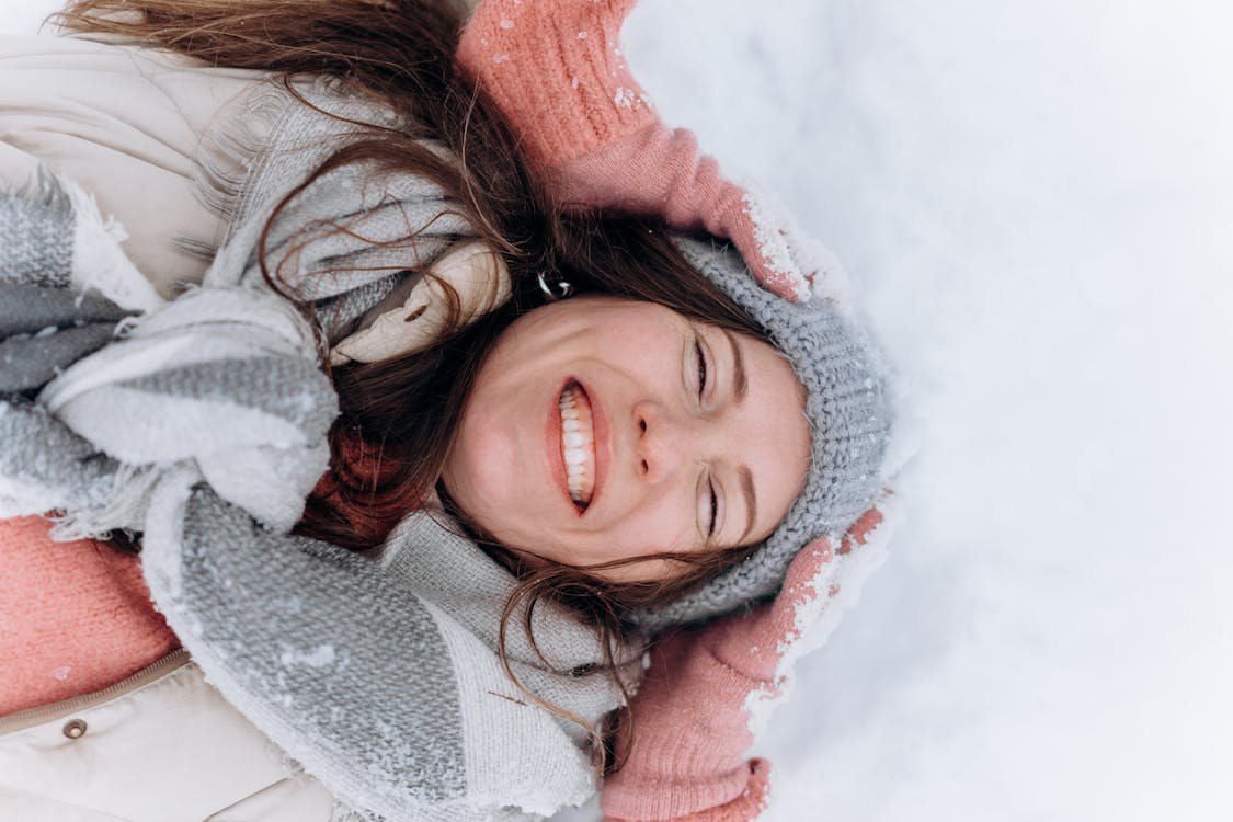 Free Top View of a Smiling Woman Lying on Snow  Stock Photo