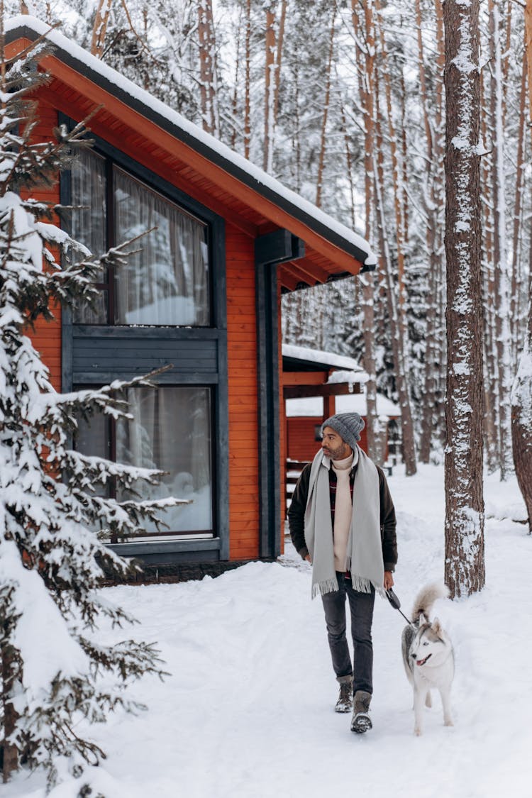 A Man And His Dog Walking In A Winter Forest