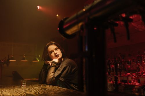 Free A woman in a dimly lit bar, seated at the counter with a contemplative look. Stock Photo