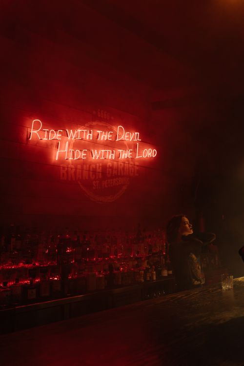 Free Moody bar scene with neon lights and a philosophical quote on the wall. Stock Photo
