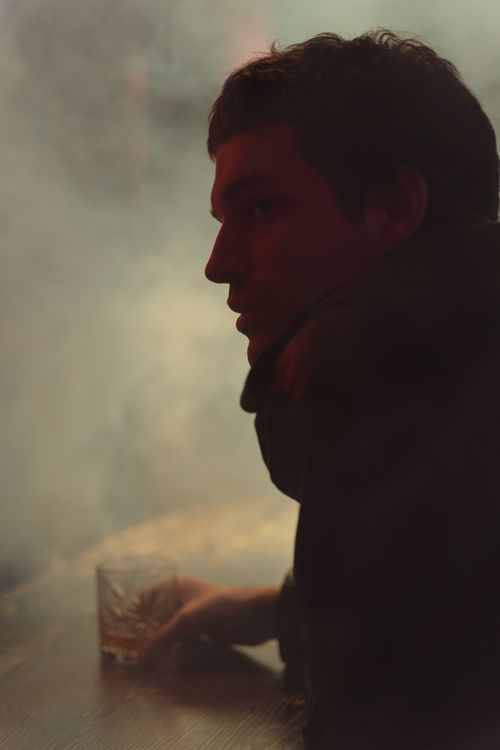 Free Man sitting at a bar with a drink, surrounded by dramatic smoke effect. Stock Photo