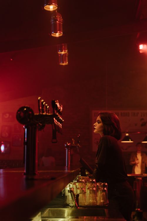 Free Atmospheric bar setting with a bartender next to beer taps under red lighting. Stock Photo