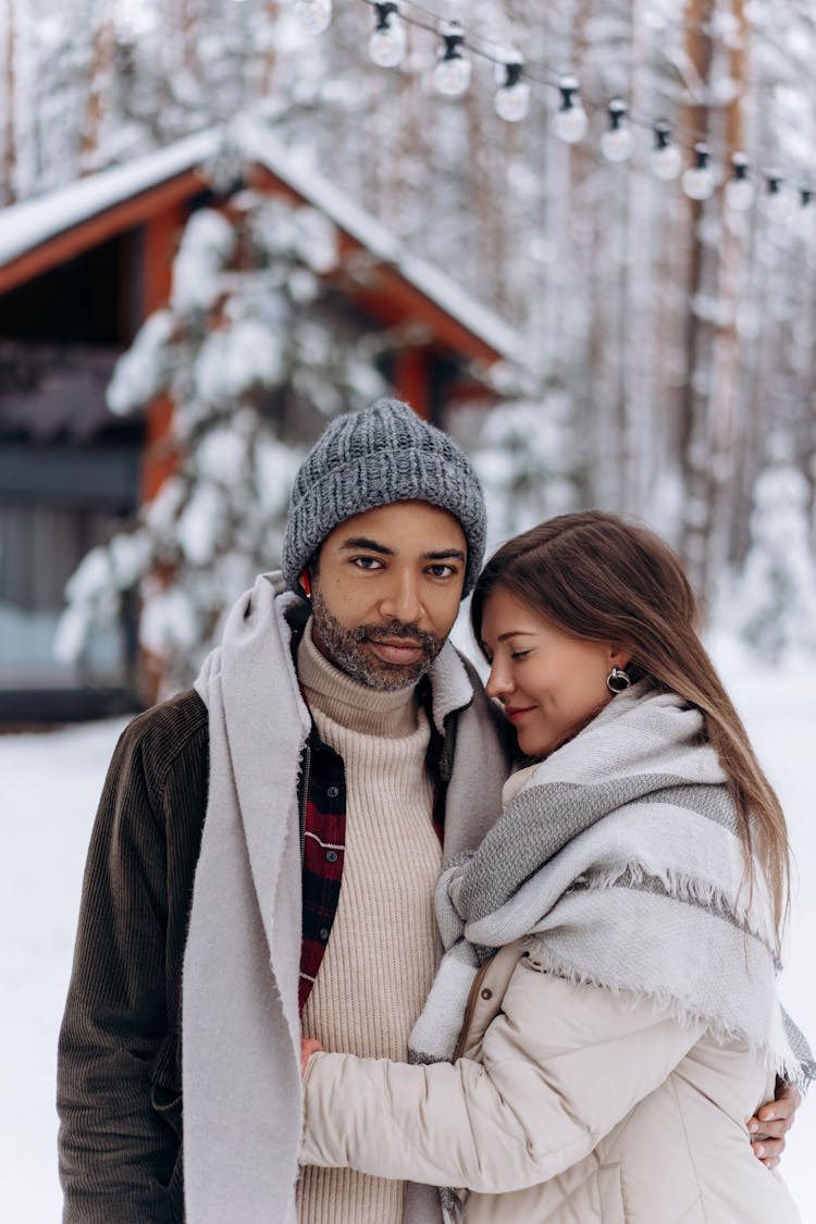 A Couple Posing Near A Cabin In A Winter Forest