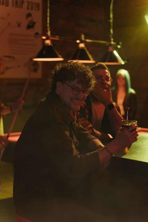 Free Men relaxing with drinks at a lively bar with dim lighting and lively atmosphere. Stock Photo