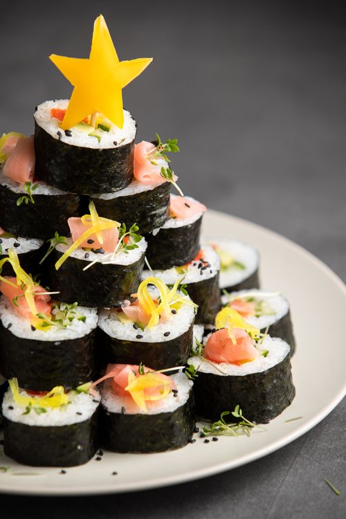 Free Vertical shot of sushi rolls arranged in a Christmas tree shape with a star garnish. Stock Photo