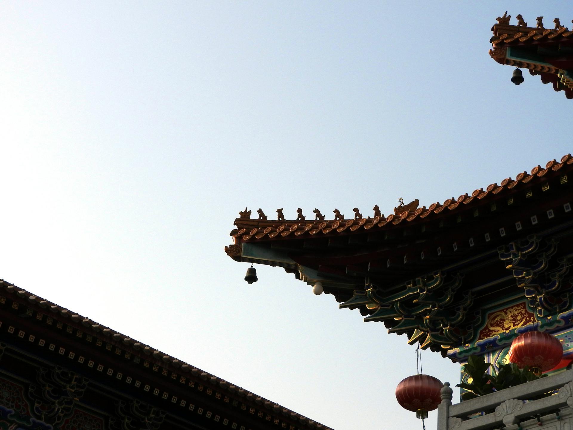 Close-up of intricate Chinese temple roof against blue sky in Hong Kong.