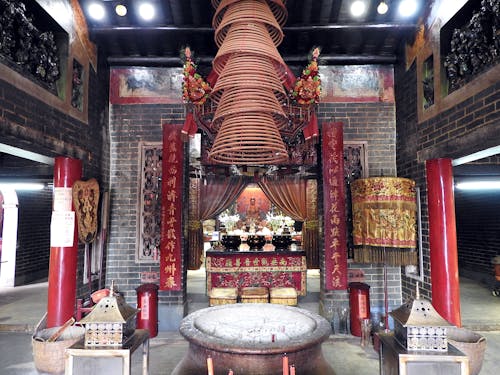 Interior of traditional Asian temple with altar and hieroglyphs near floor lamp and baskets with different decorative elements