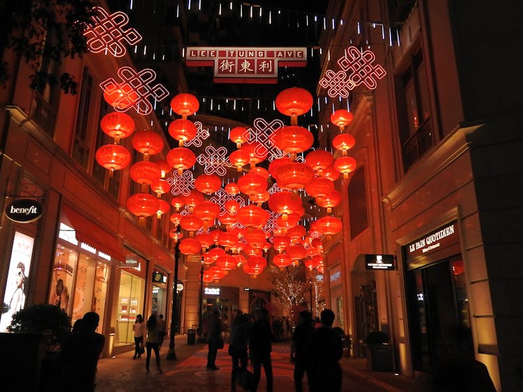 Traditional Chinese Lanterns Hanging In Street Between Buildings With People