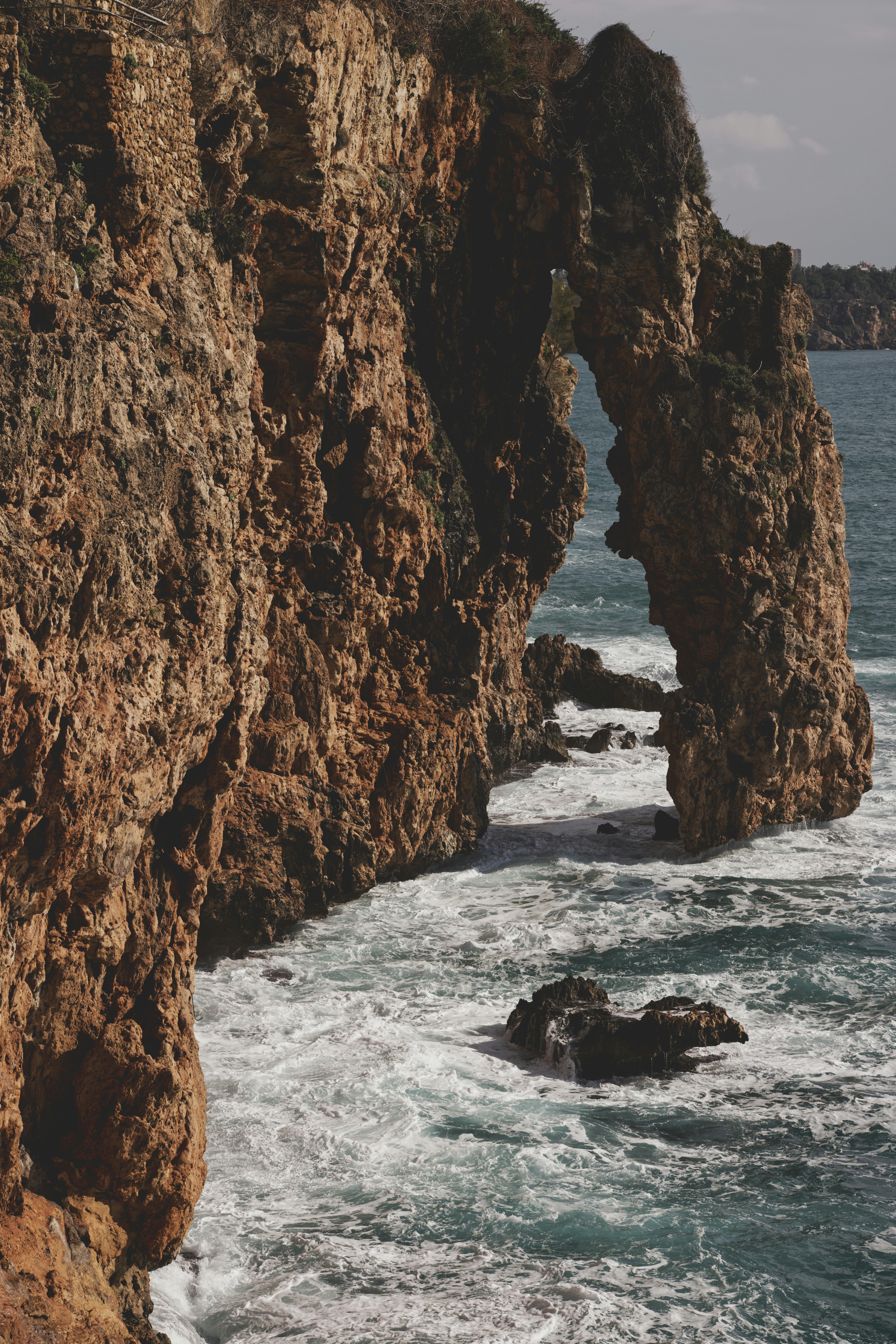 Dramatic rock formations along the Antalya coastline with crashing waves.