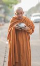 Monk Holding a Bowl Standing on the Street