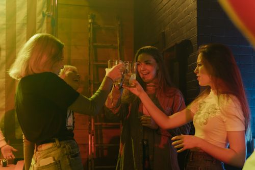 Free Four women raising glasses in a cheerful toast during a lively party. Stock Photo