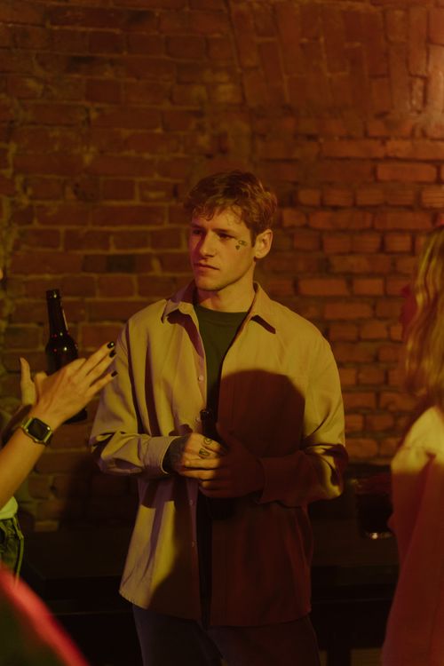 Free A group of adults having a casual conversation in a dimly lit urban bar with a brick wall backdrop. Stock Photo