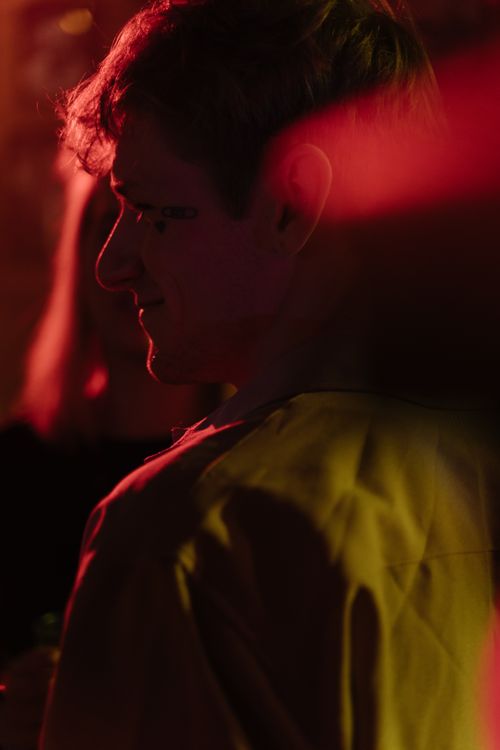 Free A man enjoys a party with moody bokeh lighting enhancing the vibrant atmosphere. Stock Photo