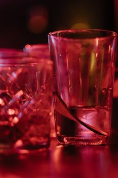 Artistic close-up of drinking glasses with red lighting, creating a moody ambiance.