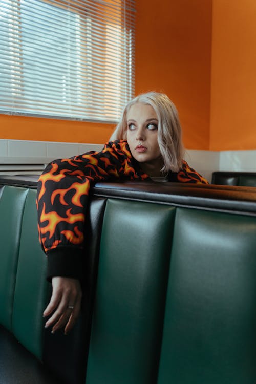 Woman in Hoodie Sitting Behind Dark Green Sofa