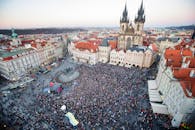 Drone view of crowd of people standing on square near gothic aged church and old town hall located in Prague