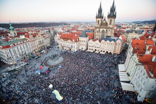 Drone view of crowd of people standing on square near gothic aged church and old town hall located in Prague