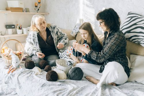 Free Three generations crocheting together on a cozy bed, showcasing family bonding. Stock Photo