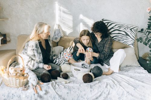 Free Grandmother, mother, and daughter enjoying knitting together at home. A warm family bonding moment. Stock Photo