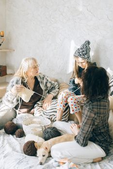 Three generations enjoying knitting and togetherness indoors.