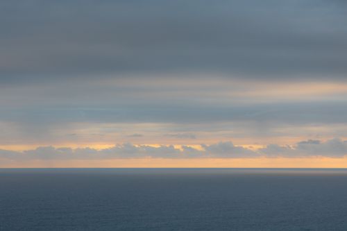 Free Serene ocean view at dawn with soft clouds and calm waters. Stock Photo