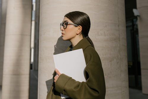 Free Woman in Green Coat Standing Beside the Concrete Column Stock Photo