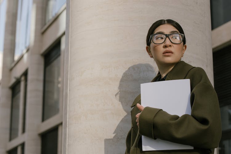 A Woman In Eyeglasses Wearing Coat While Holding Documents