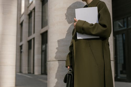 Free Person Standing Beside the Column Holding Papers and Briefcase Stock Photo