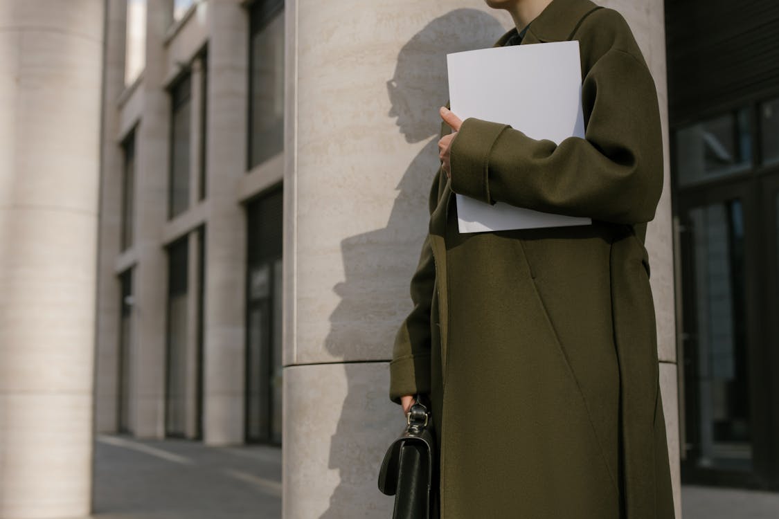 Free Person Standing Beside the Column Holding Papers and Briefcase Stock Photo