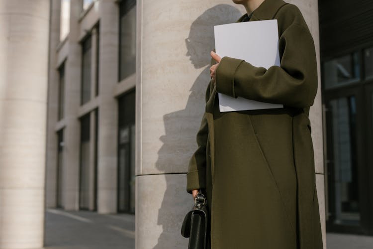 Person Standing Beside The Column Holding Papers And Briefcase