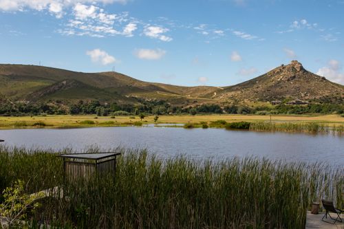 Free Serene landscape of a lake surrounded by hills under a clear blue sky. Stock Photo