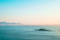 在柔和的早晨天空下，宁静的海景中可见遥远的岛屿和山脉