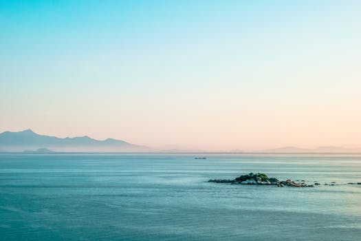 在柔和的早晨天空下，宁静的海景中可见遥远的岛屿和山脉