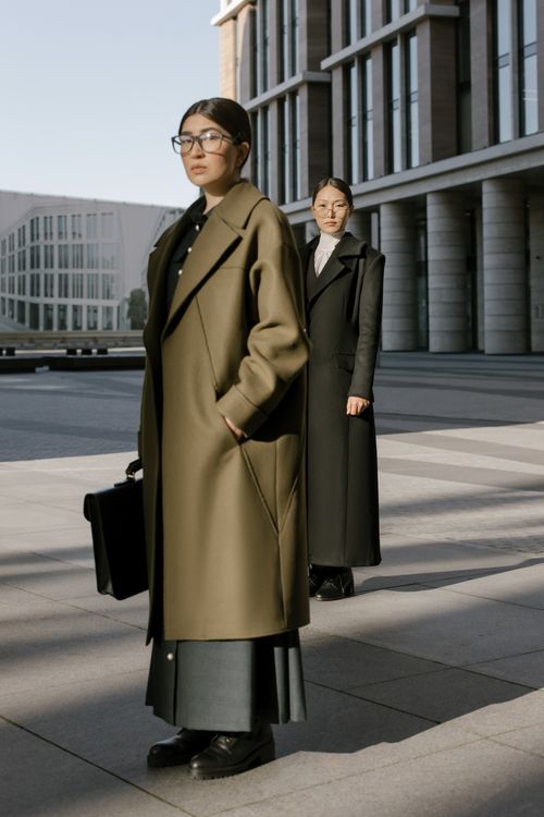 Free Two Asian women in fashionable coats standing outside a modern building. Stock Photo