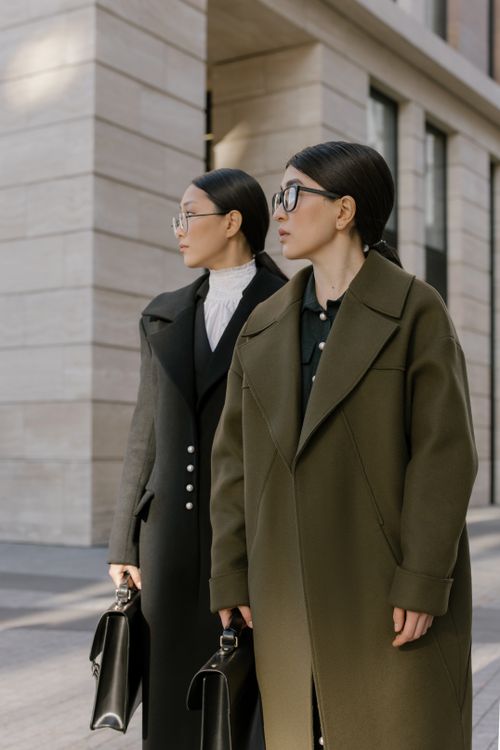 Free Two stylish women in elegant coats standing outdoors with briefcases, showcasing urban fashion. Stock Photo