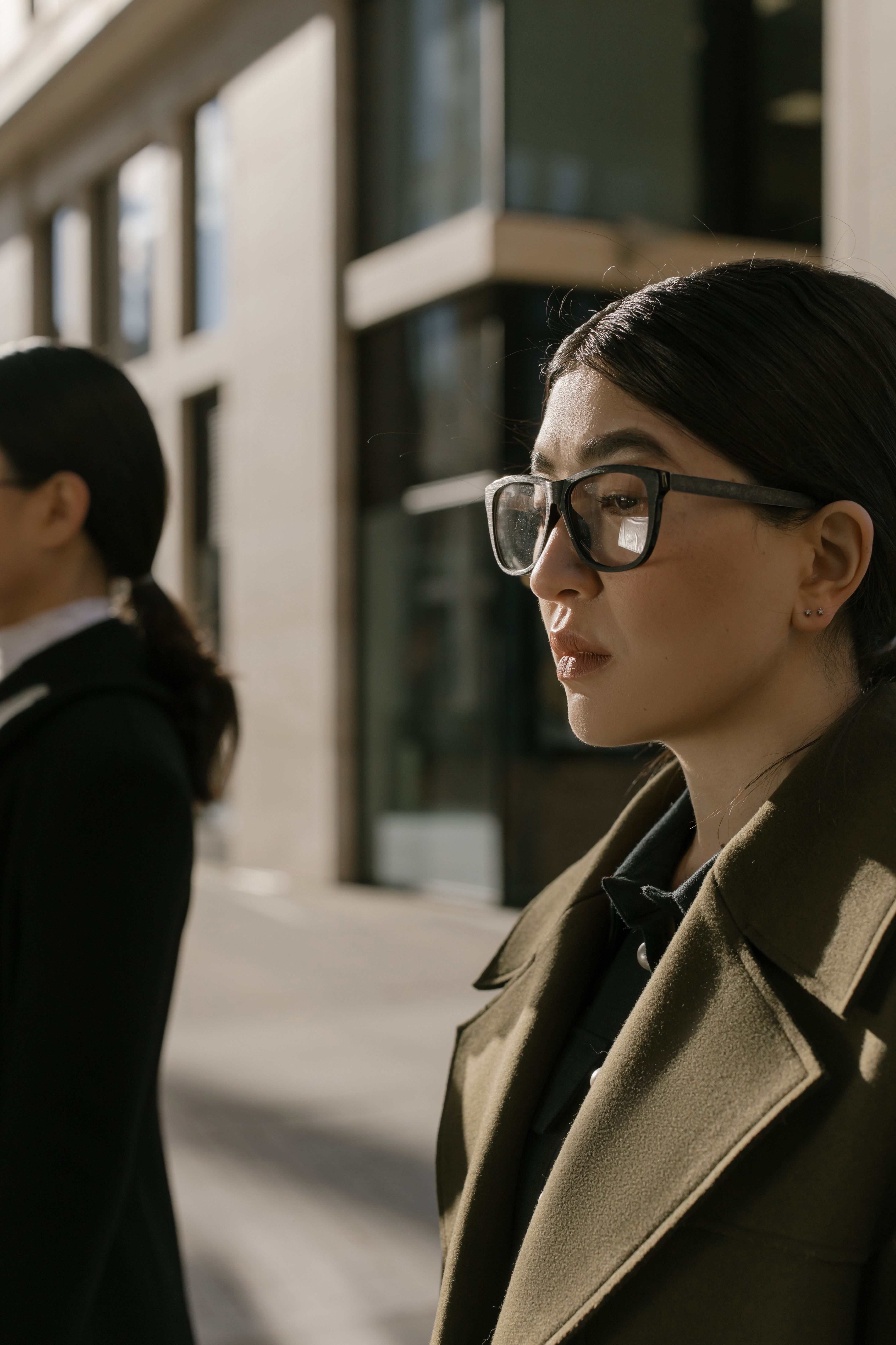 Asian woman wearing glasses walking confidently in urban street.