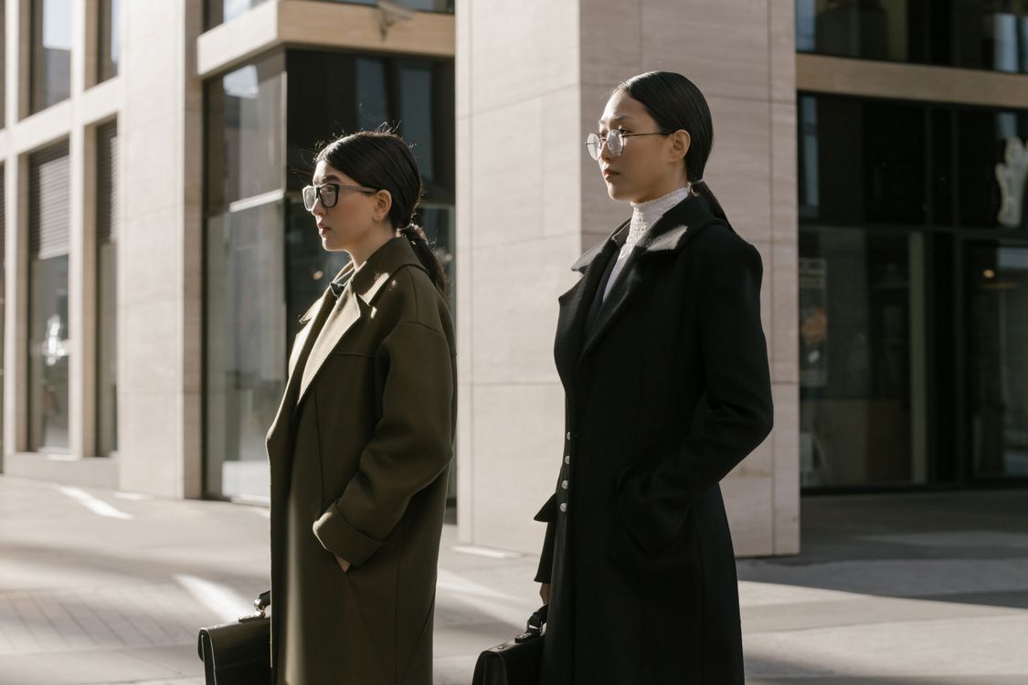 Woman in Coats Standing Together Near a White Building · Free Stock Photo