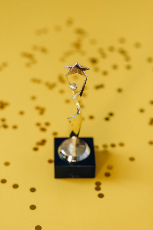 Free Silver star trophy on yellow background with confetti. Perfect for success concepts. Stock Photo