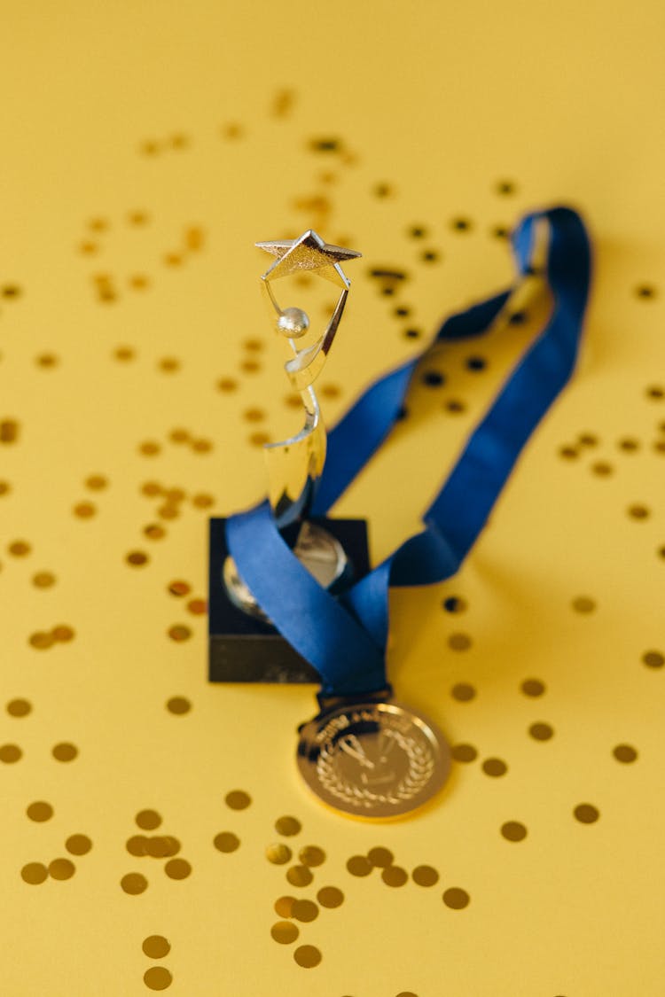 A Medal And A Trophy On Yellow Surface