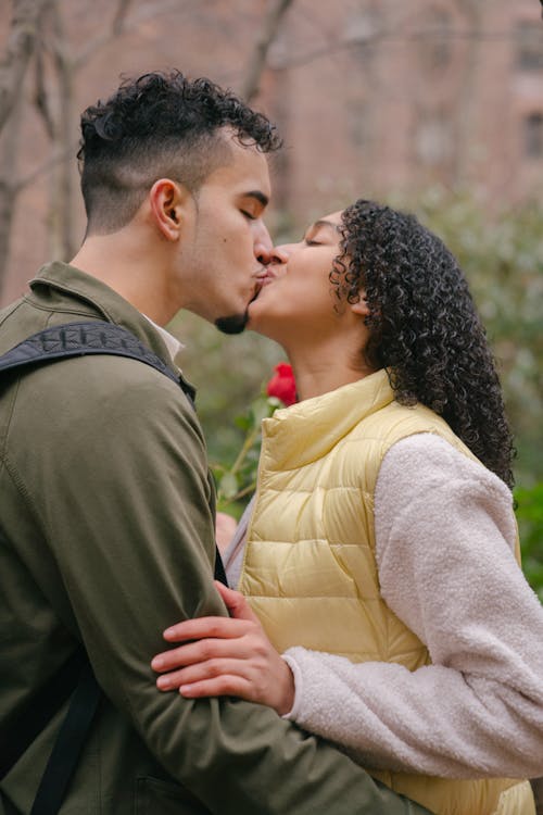 Latin American couple kissing near trees in park